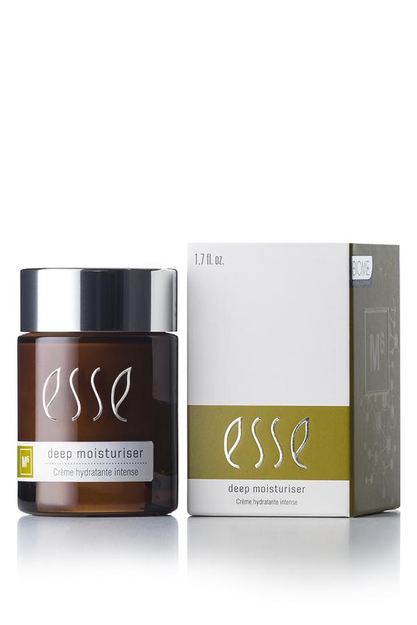 A brown jar of Esse Deep Moisturiser with a silver lid is placed next to its white and olive-green box. Both the jar and the box display the brand name "Esse" along with product details. The jar contains 1.7 fl. oz. (50 ml) of deeply hydrating cream.