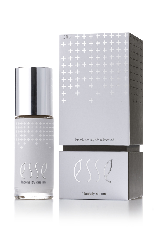 The Esse Intensity Serum features a minimalist design with small plus signs and the word "esse" on both its sleek silver-capped bottle and matching silver-and-white box.