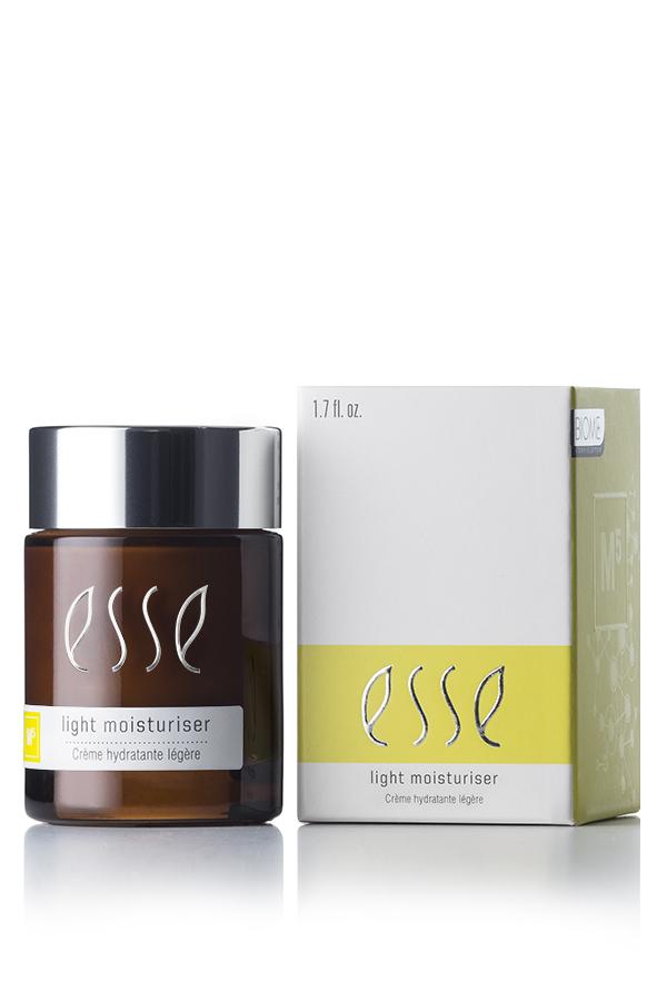 A 1.7 fl. oz. jar of Esse Light Moisturiser is showcased beside its matching white and yellow packaging. The jar features a dark amber hue, a black cap, and the product name "Esse Light Moisturiser" is prominently displayed in white text on both the jar and the box.