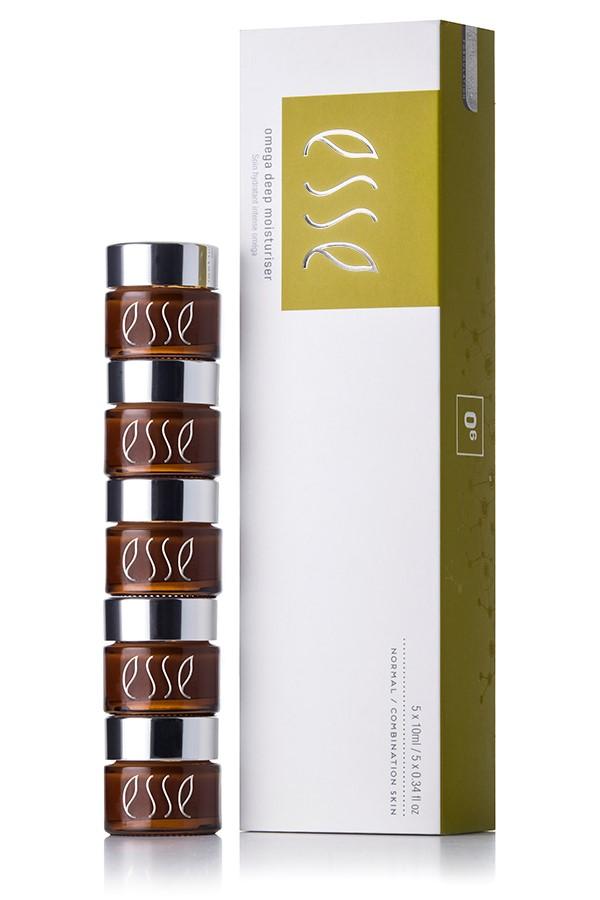 A stack of five small brown jars with silver lids, labeled "Esse Omega Rich Moisturiser," is placed next to a white and green box with the same branding. The box displays product information and appears to contain skincare items.