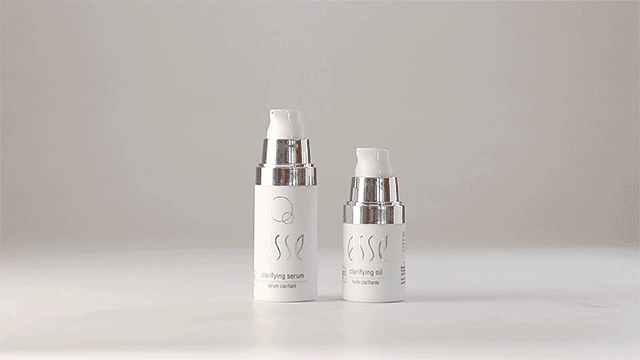Two white skincare product bottles with silver pumps are placed on a flat surface. The taller bottle is labeled "Esse Clarifying Cleanser," while the shorter bottle is labeled "Clarifying Oil." Both bottles have the brand name "Esse" printed on them in an elegant font.