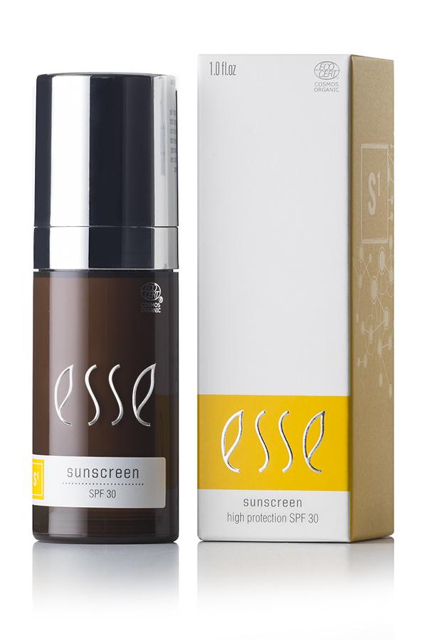 An Esse Sunscreen bottle with SPF 30 stands next to its box packaging. The brown bottle, featuring a black cap, showcases the Esse logo and product details in white. The light brown box includes yellow and white labels that display the same product information.