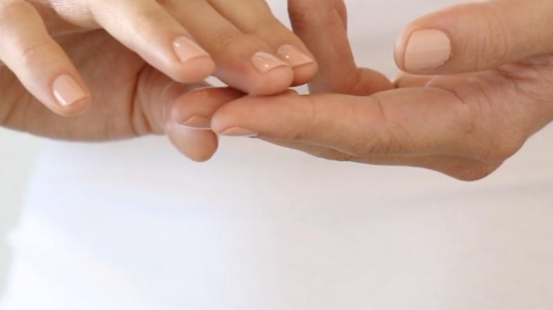 Close-up of two hands with manicured nails; one hand gently cradles the fingertips of the other. The nails are adorned with a light, neutral polish, drawing all attention to their elegance against a blurred background. Enhance your skincare routine with Esse Probiotic Serum for naturally beautiful hands.