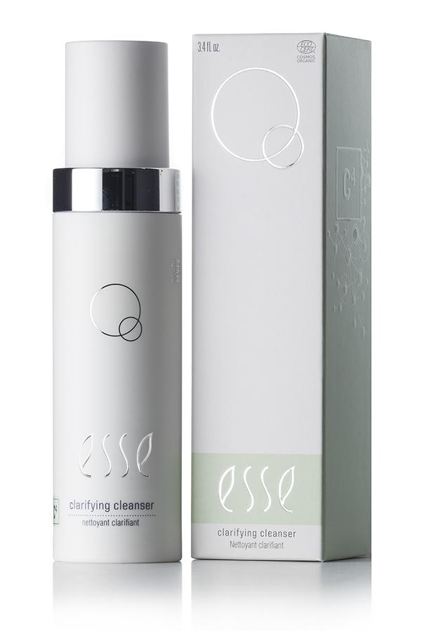 An image of the Esse Clarifying Cleanser, a skincare product in a sleek white bottle with a silver cap, is presented alongside its matching white and light green packaging box. Both the bottle and box showcase simple, minimalist design elements.